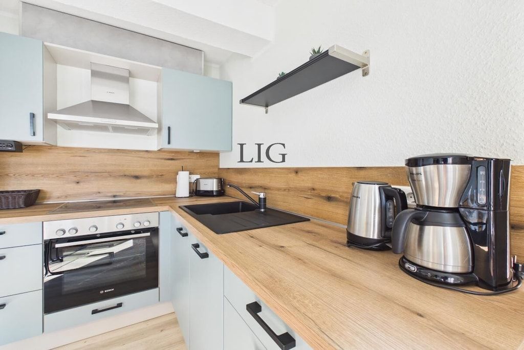 Ett modernt kök med en inbyggd ugn, en kaffebryggare och en diskho.