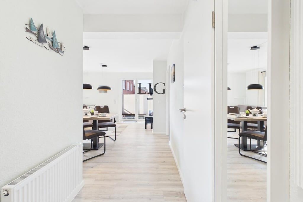A hallway leading to a dining area with a white radiator, a door with a handle, and a wall-mounted decoration.