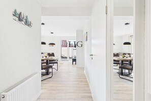 A hallway leading to a dining area with a white radiator, a door with a handle, and a wall-mounted decoration. - Holiday apartment Dünengras (Langeoog)