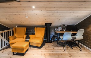 A room with wooden ceiling and walls, a desk with a computer, two armchairs, and a white office chair. - 4 bedroom stunning home in Flå (Flå)
