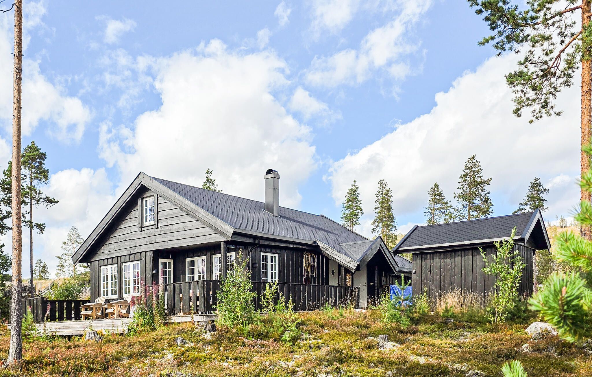 A cabin with a sloped roof, large windows, and a deck area.