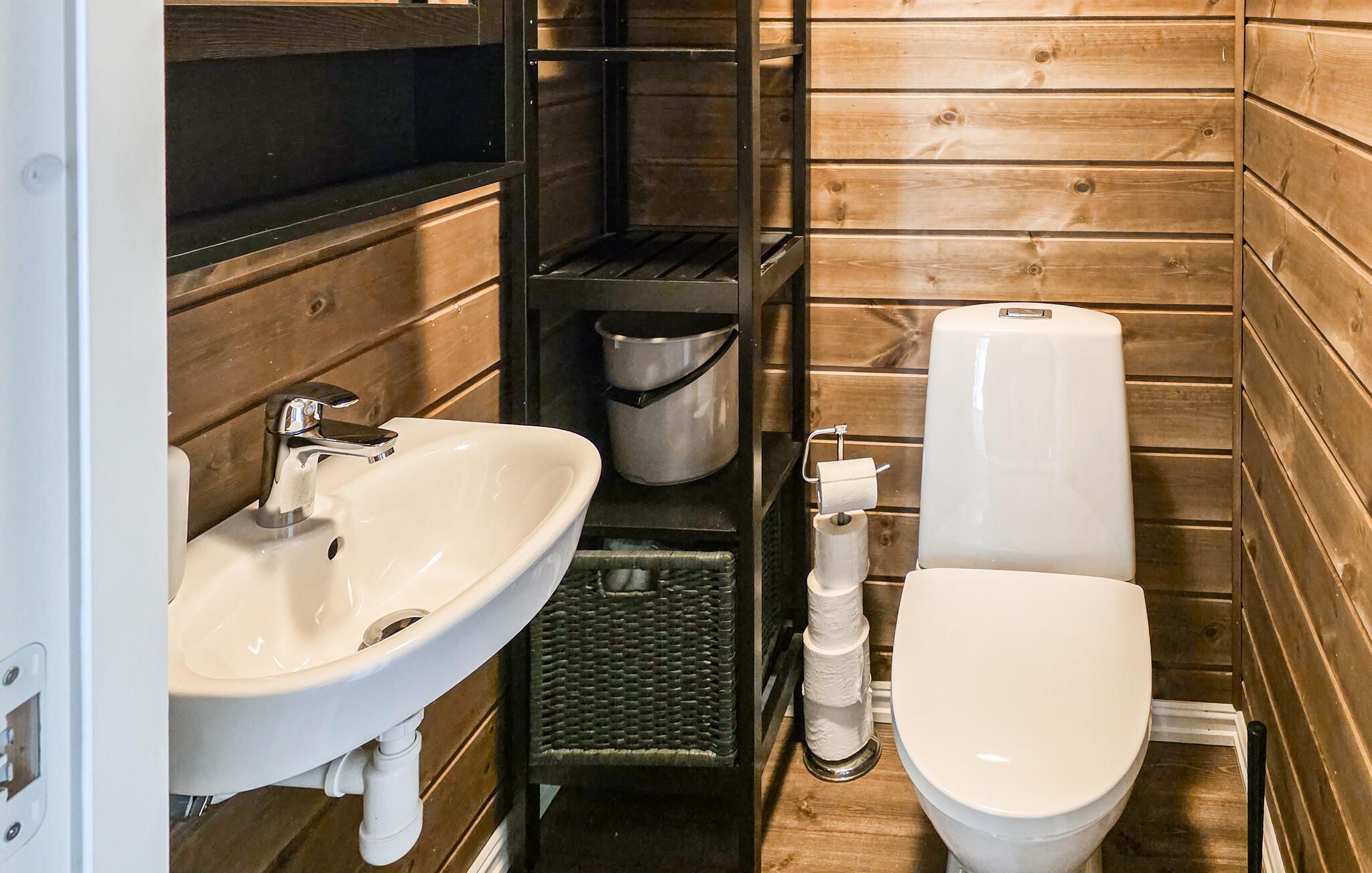 Ein kleines Badezimmer mit Waschbecken, Toilette und einem Metall-Abfalleimer.