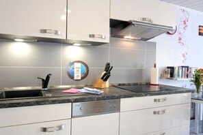 Een moderne keuken met een roestvrijstalen spoelbak, een messenblok en een geïntegreerde vaatwasser.
