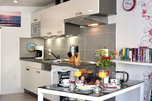 Cozinha moderna com  área de refeições, equipada com micro-ondas, fogão e máquina de café.