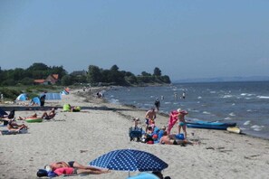 Ein Strand mit Menschen, die sonnenbaden, schwimmen und spielen.