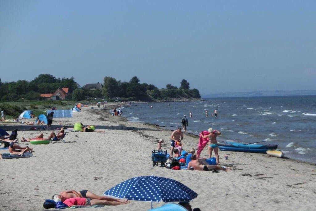 A beach with people sunbathing, swimming, and playing.