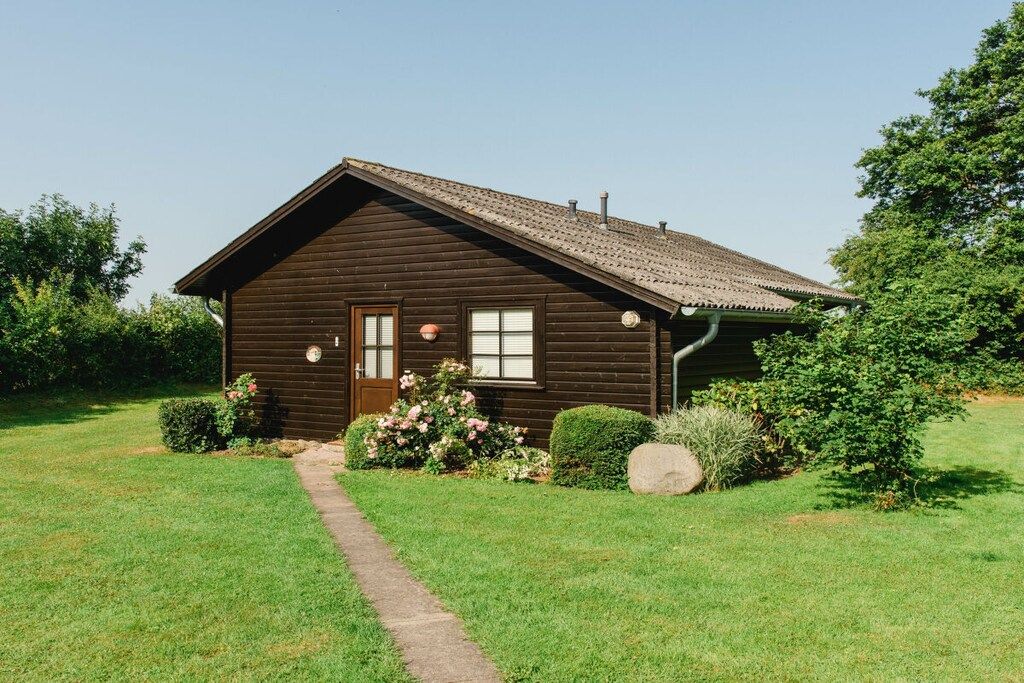 Une cabane en bois avec un toit en pente, une porte d’entrée et un petit porche.