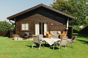 A wooden cabin with a patio area featuring a table and chairs, surrounded by a well-maintained lawn. - Struve 1 on the Kastanienhof (Quern)