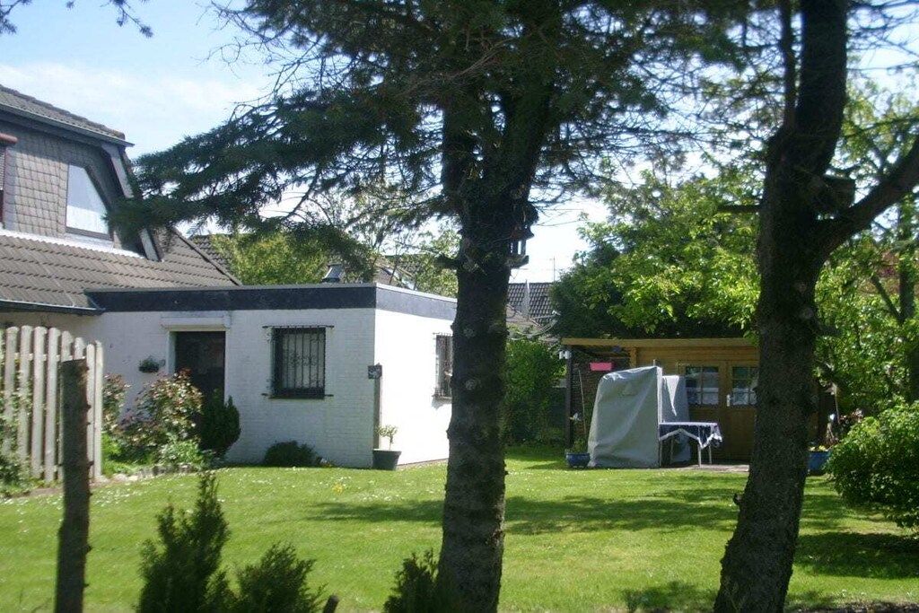 Il s’agit d’une propriété résidentielle comprenant une maison blanche, une cour clôturée et un espace extérieur abrité.