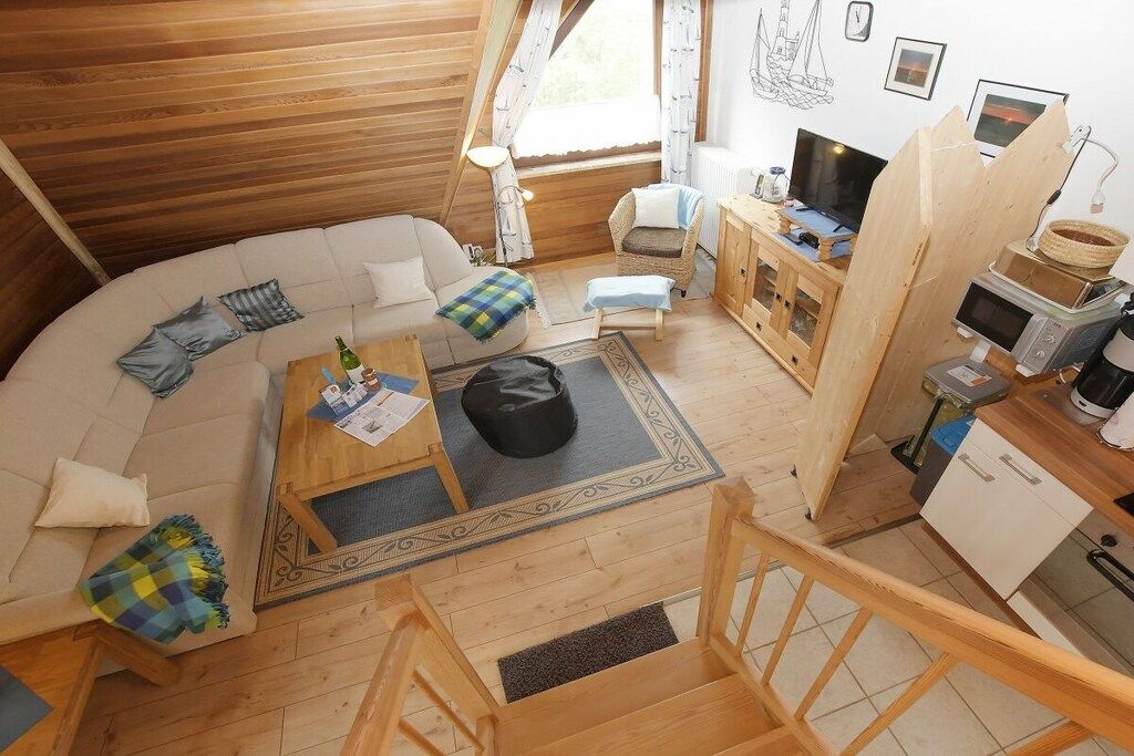 Een knus, houten kamer met een gebogen bank, een klein bijzettafeltje, een televisie en een kitchenette.