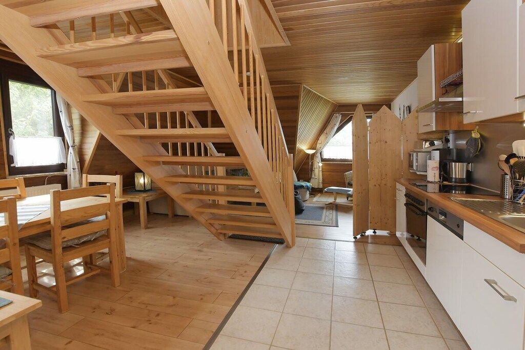 Un intérieur en bois comprenant un escalier, un coin cuisine et une table à manger.