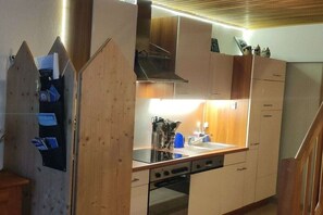 Cocina compacta con armarios de madera, horno empotrado y campana extractora de acero inoxidable.