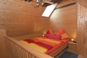 Una cabaña de madera con una cama individual, una mesita de noche y una pequeña mesa.