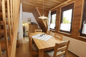 A wooden dining area with a table, chairs, and a hanging light fixture. - Holiday apartment with 2 bedrooms (Büsumer Deichhausen)