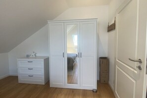 A room with a white wardrobe, a small bedside table, and a door. - Holiday apartment in Hürup with swimming pool (Hürup)