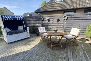 A wooden deck with a white outdoor sofa and a small table with chairs. - Holiday apartment in Hürup with swimming pool (Hürup)