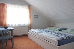 A bedroom with a bed, a desk, and a window with curtains. - Holiday apartment with 2 bedrooms (Malente OT Timmdorf)