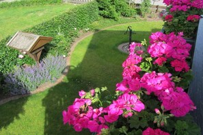 Un jardín con un letrero de madera, una cama de flores circular y flores rosadas vibrantes.