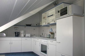 A kitchen with white cabinets, a microwave, and a coffee maker. - Holiday apartment with 2 bedrooms (Malente OT Timmdorf)