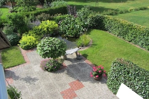 A garden with a pond, various plants, and a stone bench. - Holiday apartment with 2 bedrooms (Malente OT Timmdorf)