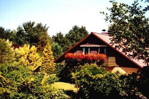 Una casa con techo rojo, rodeada de exuberante follaje y árboles.