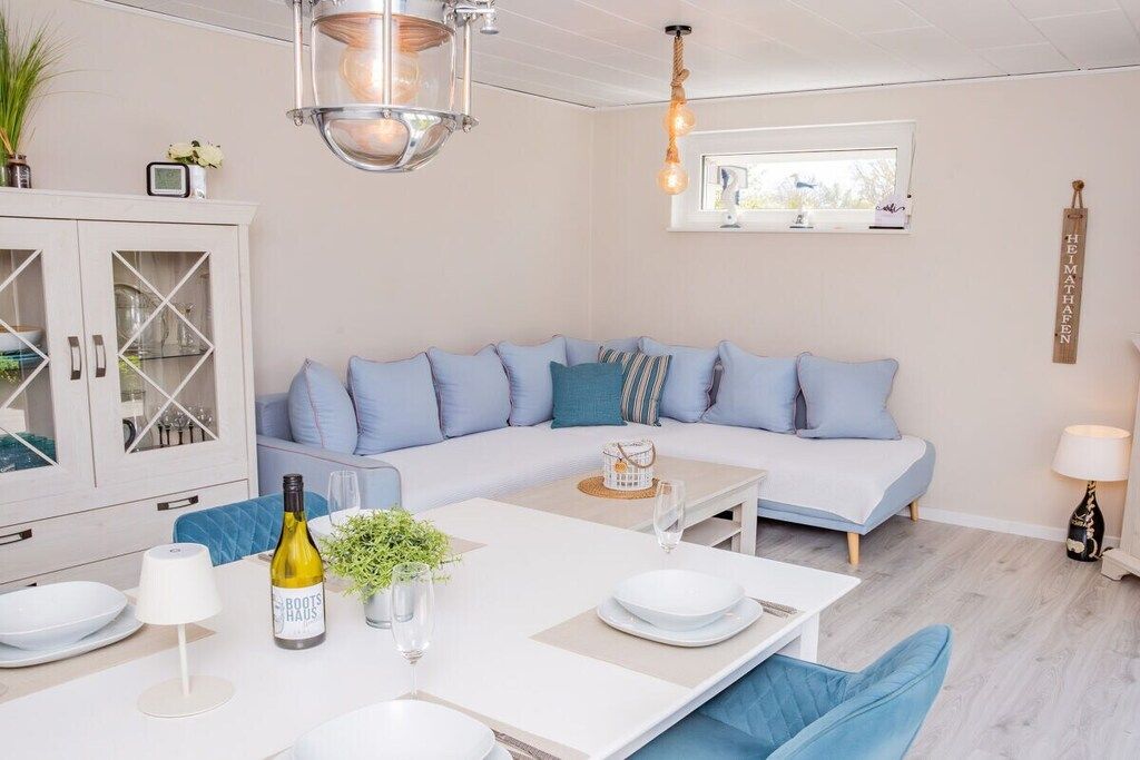 A modern living room with a sectional sofa, a dining table set for two, and a cabinet with glass doors.