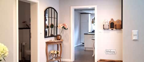 Un intérieur moderne avec un couloir central, des spots encastrés au plafond, un tapis décoratif et un panneau d’accueil.