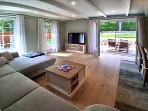 A spacious living room with a sofa, a coffee table, and a flat-screen TV. - Holiday Home 'Holidate-Inn' with Private Terrace, Private Garden and Wi-Fi (Stadum)