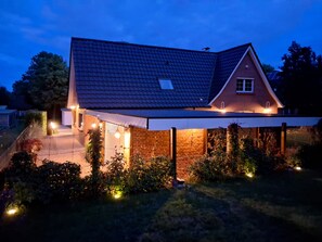 A house with a sloped roof, brick walls, and a covered porch with lights. - Holiday Home 'Holidate-Inn' with Private Terrace, Private Garden and Wi-Fi (Stadum)