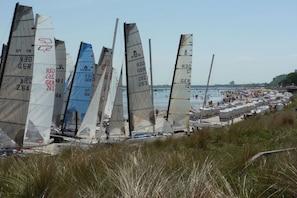 A row of sailboats docked along a beach with people and boats in the background. - Holiday apartment with 2 bedrooms (Scharbeutz)