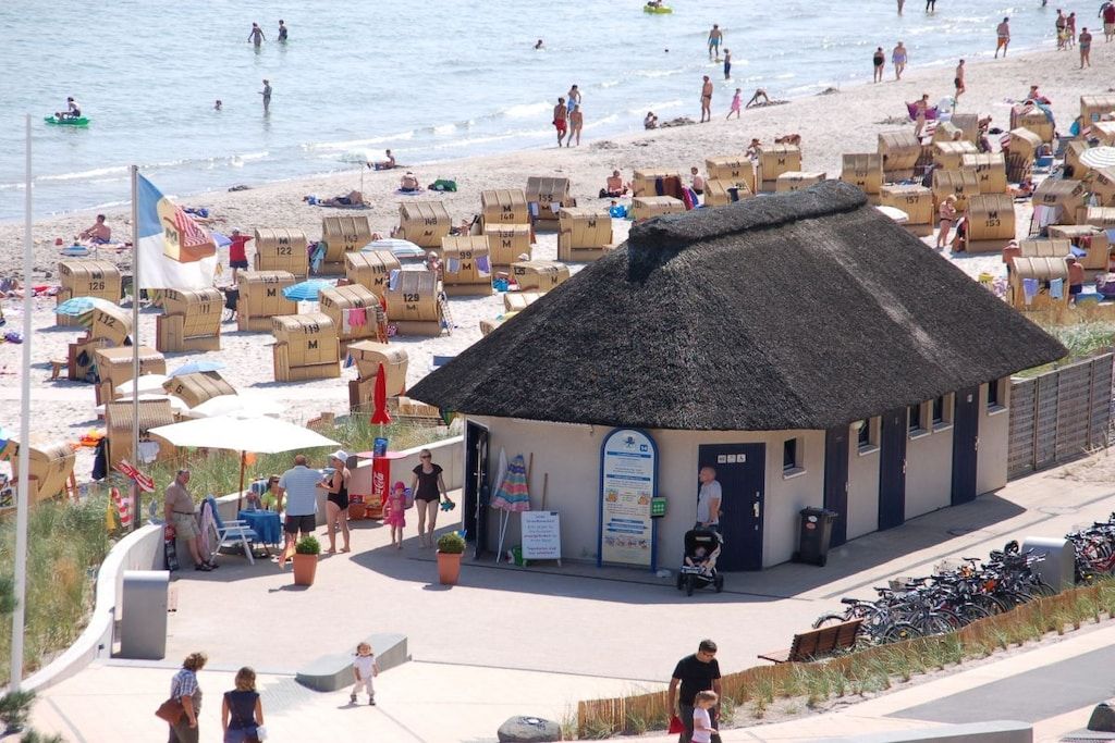 A beachside building with a thatched roof, surrounded by beach huts and a sandy beach.