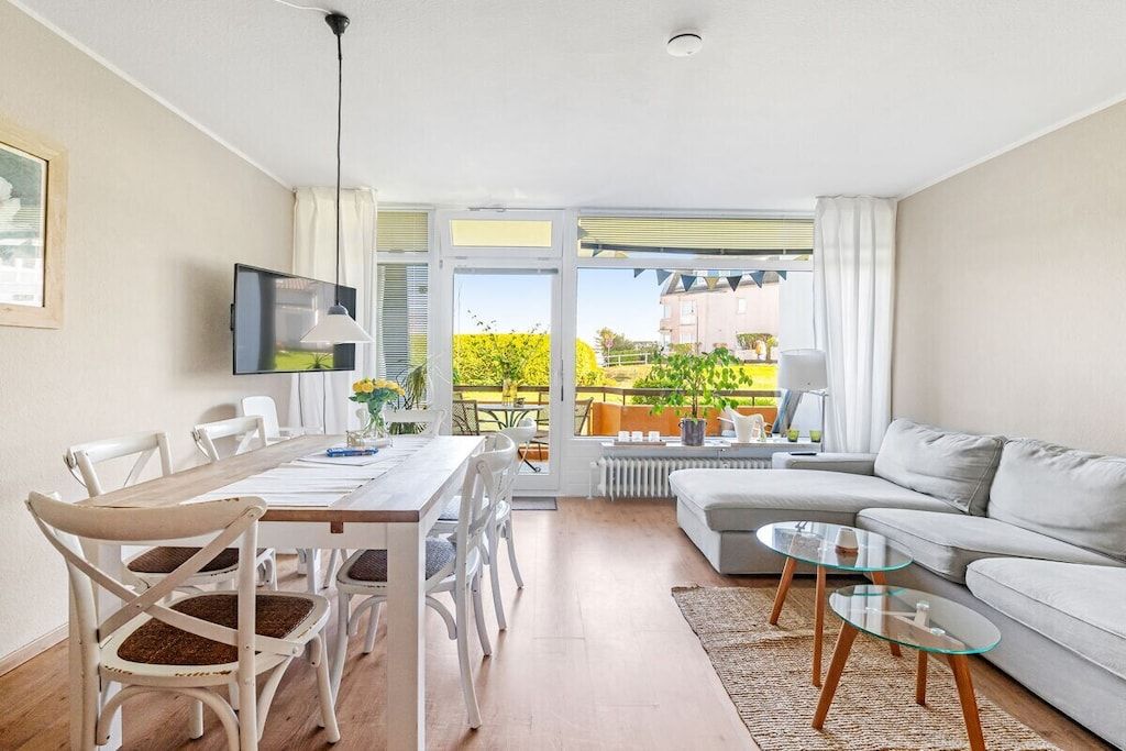 A modern living room with a dining area, a sofa, and a television.