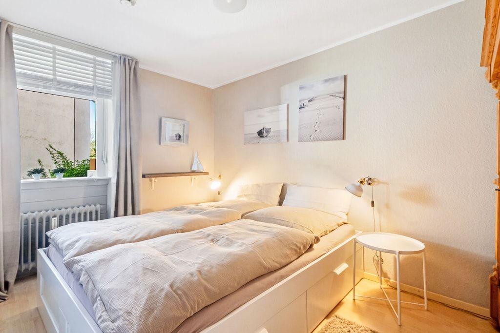 A bedroom with a bed, bedside table, and a window with curtains.