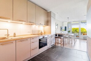 A modern kitchen with integrated appliances, a dining area with a view, and a spacious layout. - Holiday apartment with 2 bedrooms (Scharbeutz)