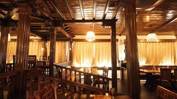 L’intérieur d’un restaurant avec des poutres en bois, un escalier et des tables dressées pour le service.
