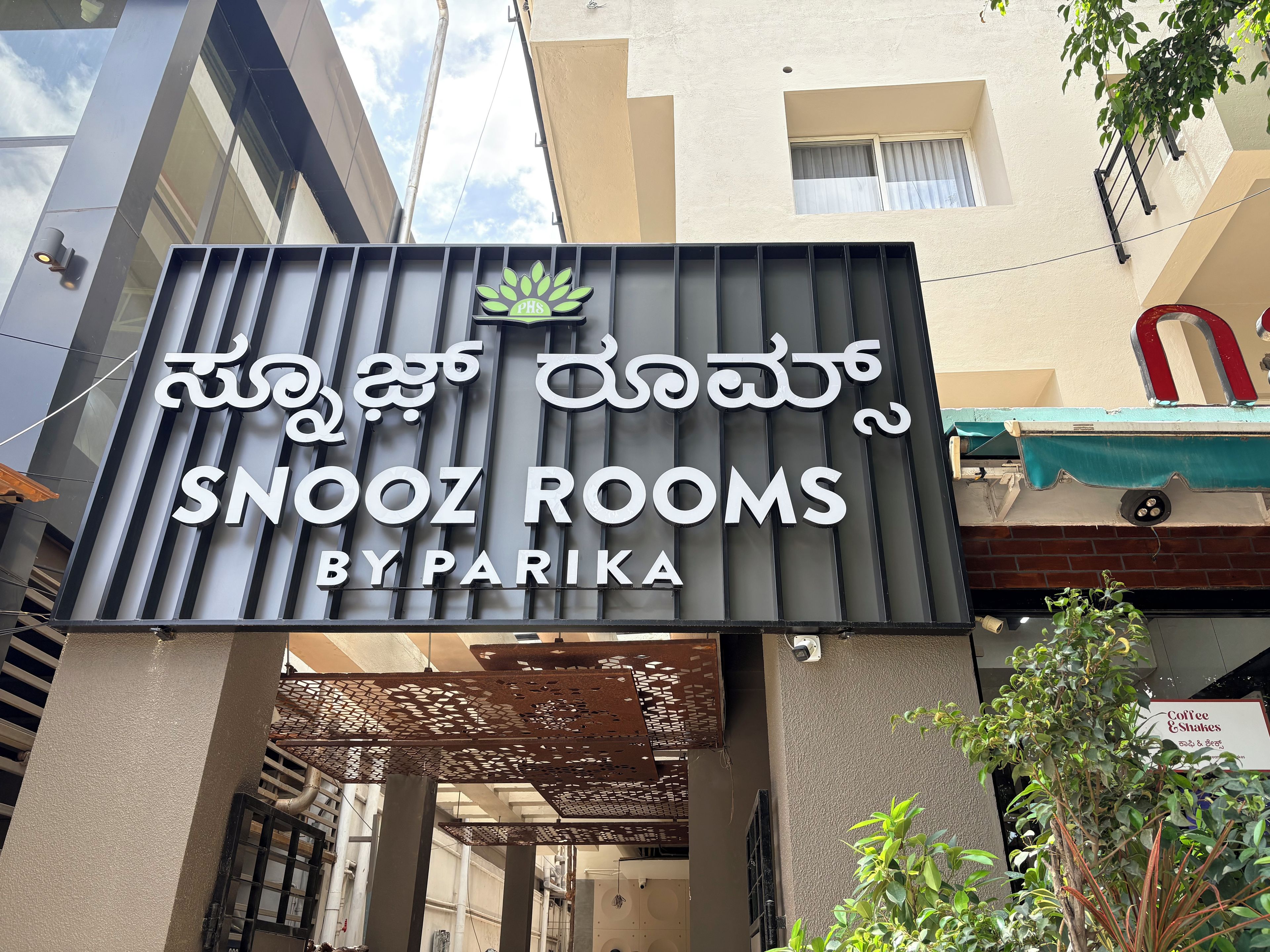 A hotel sign with 'SNOOZ ROOMS BY PARIKA' written in English and another language.