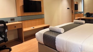 A hotel room with a bed, a desk, a chair, a flat-screen TV, a mirror, and a coffee maker. - Snooz Rooms By Parika A VYDA Hotel (Bengaluru)