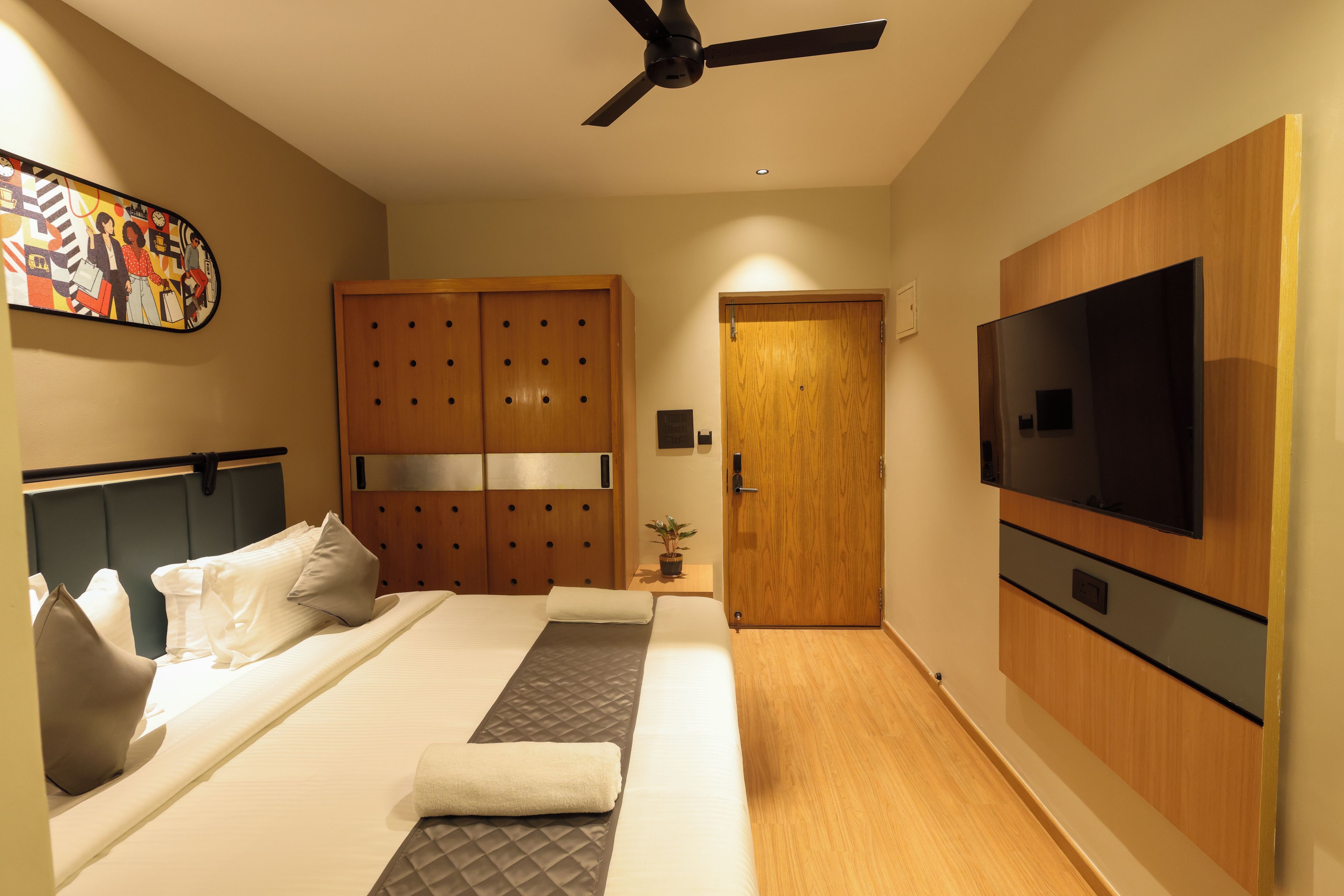 Une chambre d’hôtel équipée d’un lit, d’une télévision, d’une armoire et d’un ventilateur de plafond.