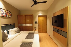 Habitación de hotel con cama, televisión, armario y ventilador de techo.
