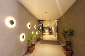 A corridor with circular light fixtures on the wall, potted plants, and a sign indicating the direction to the 3rd floor. - Snooz Rooms By Parika A VYDA Hotel (Bengaluru)