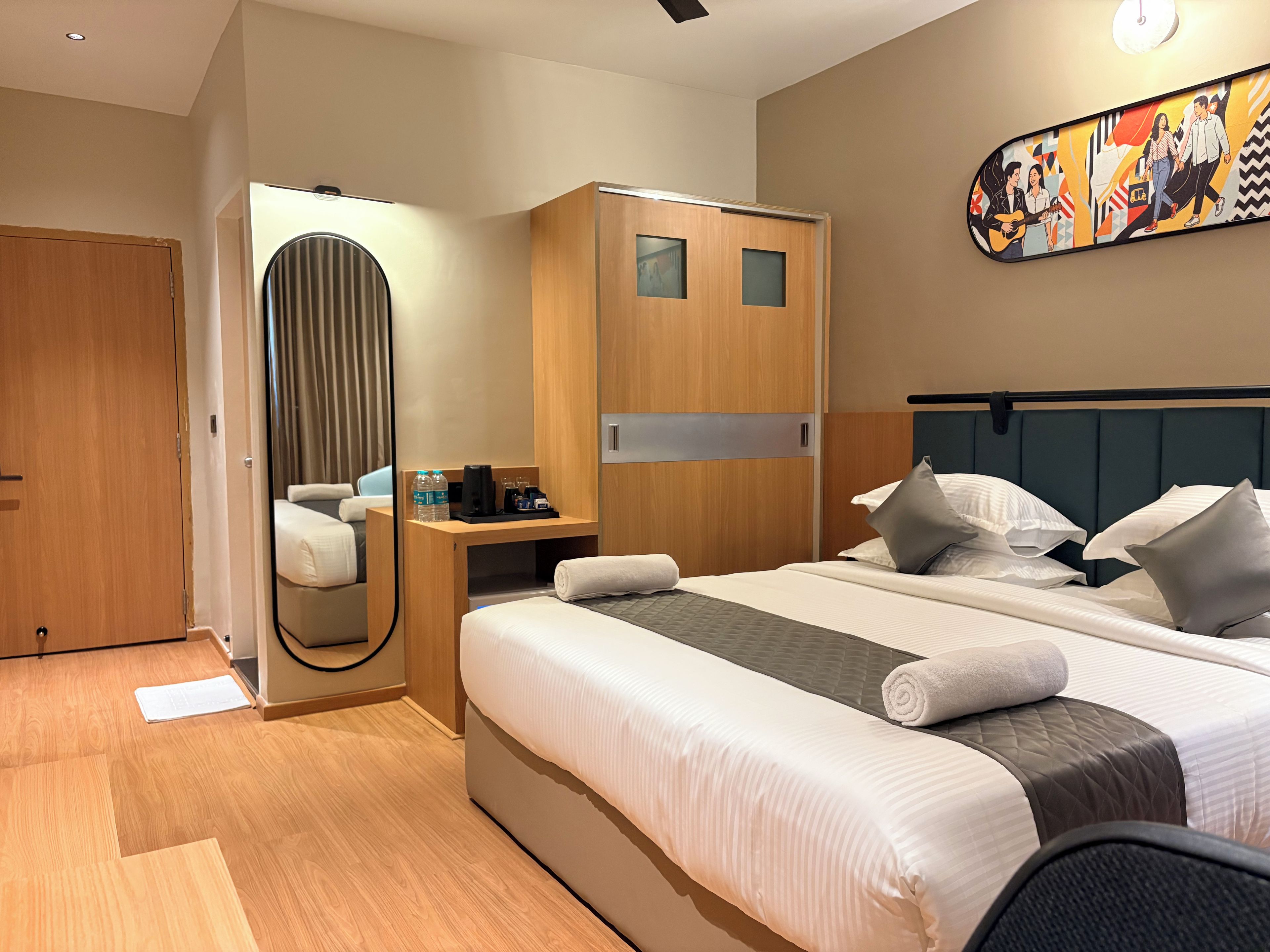 Een hotelkamer met een bed, nachtkastje en een spiegel.