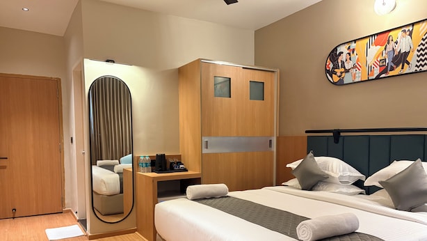 A hotel room with a bed, bedside table, and a mirror. - Snooz Rooms By Parika A VYDA Hotel (Bengaluru)