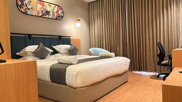 Een moderne hotelkamer met een groot bed, een bureau, een stoel, een hoofdbord, een kunstwerk aan de muur en een gordijn.