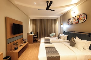 Una habitación de hotel con una cama, un escritorio, una silla, un televisor y un ventilador de techo.