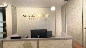 A reception desk with a patterned partition, a mounted computer, and a pendant light. - Snooz Rooms By Parika A VYDA Hotel (Bengaluru)