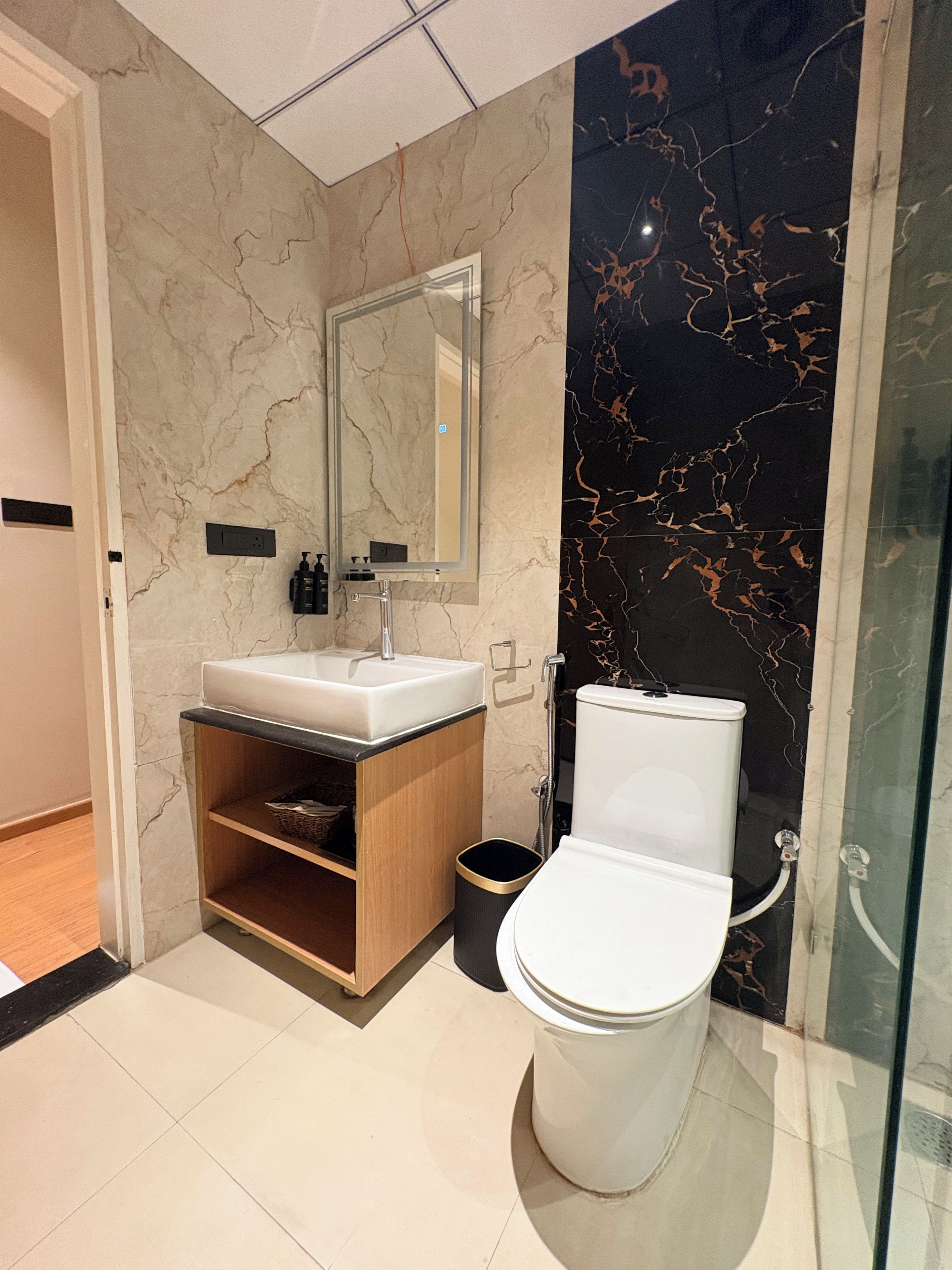 Een moderne badkamer met een wit toilet, een wastafel met spiegel en een douche.