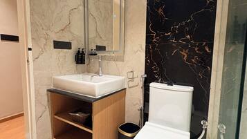Een moderne badkamer met een wit toilet, een wastafel met spiegel en een douche.