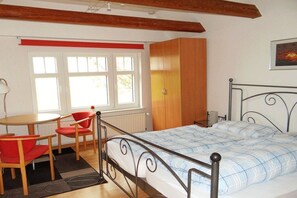 A bedroom with a bed, a wooden wardrobe, a window with blinds, a chair, and a table. - Holiday apartment in Welt with swimming pool (Welt)