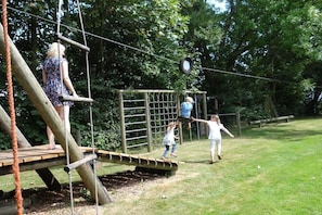 A playground with wooden structures, ropes, and a netted area. - Holiday apartment in Welt with swimming pool (Welt)