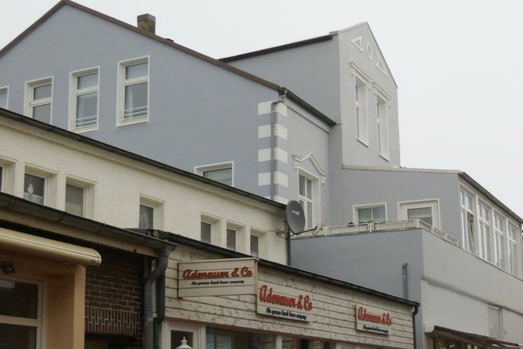 Ein Gebäude mit mehreren Schaufenstern, darunter 'Adenauer & Co.' und 'Adenauer & Co. KG'.